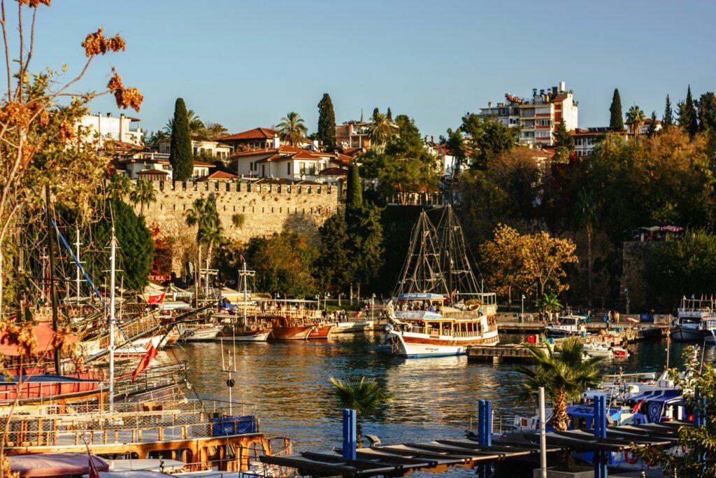 Altstadthafen von Antalya mit Ausflugsschiffen und Stadtmauer im Abendlicht