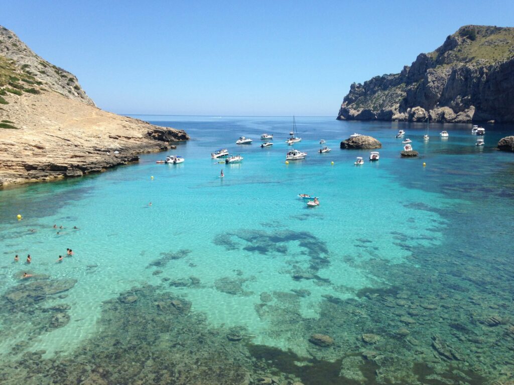 Türkise Bucht Cala Bóquer bei Pollença auf Mallorca mit ankernden Booten zwischen Kalkfelsen