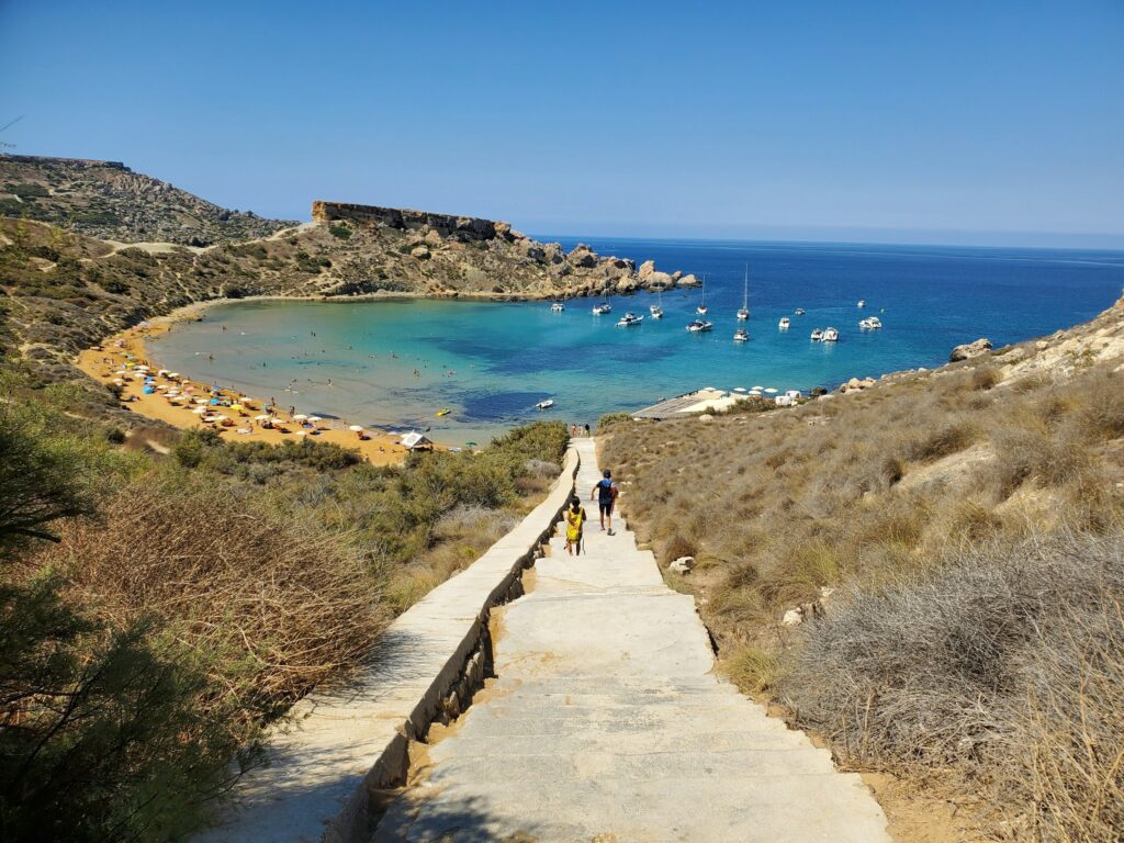 Treppenweg hinab zur türkisen Bucht Għajn Tuffieħa auf Malta mit Booten und Sandstrand